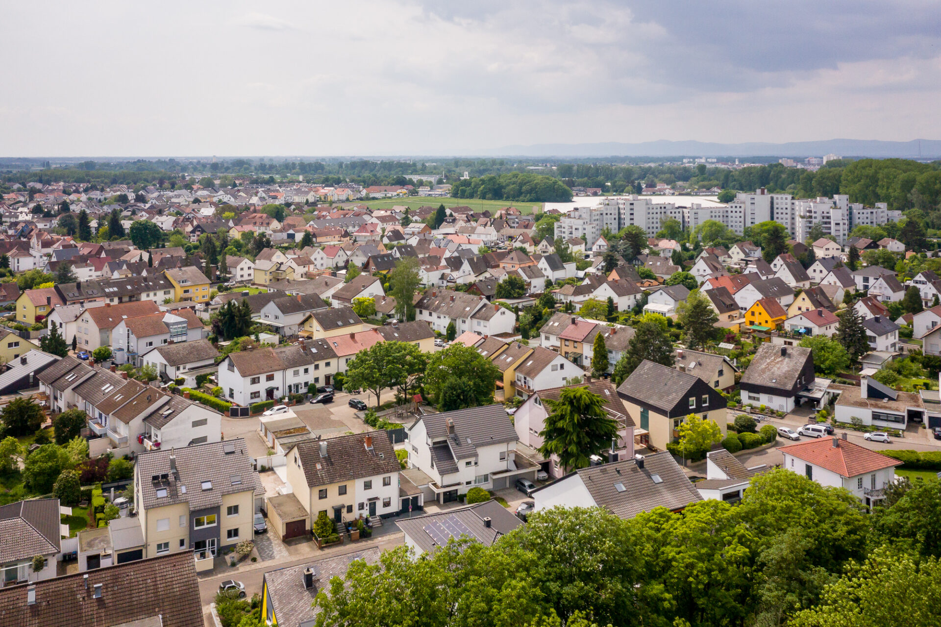 Luftaufnahme von Neuhofen mit Häuserreihen und Mehrfamilienhäusern mit vereinzelten Bäumen an einem bewölkten Tag.